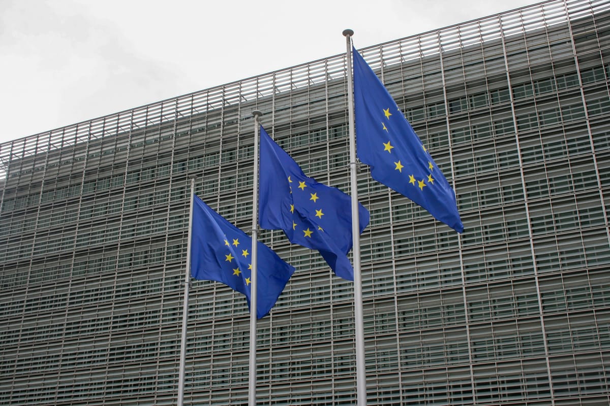 Drei EU-Flaggen wehen vor einem modernen Gebäude in Brüssel, Sitz der Europäischen Kommission