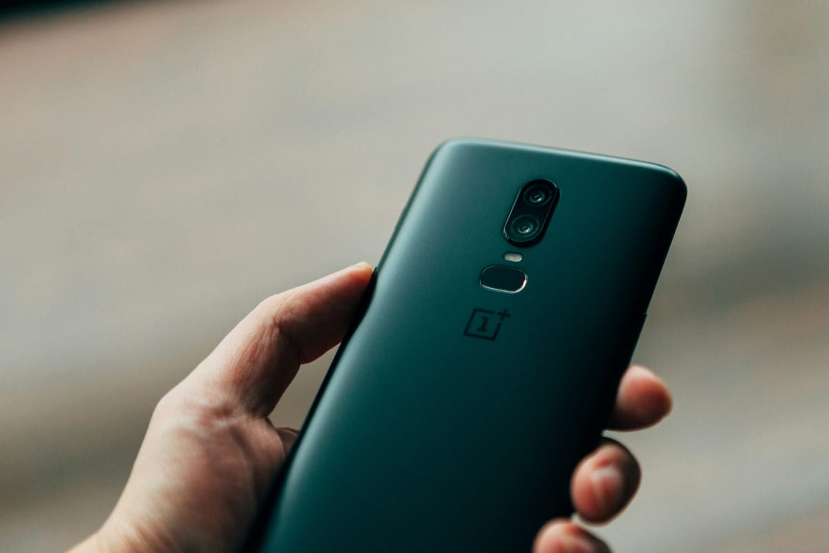Person, die ein schwarzes OnePlus-Smartphone mit auffälliger Rückseite in der Hand hält
