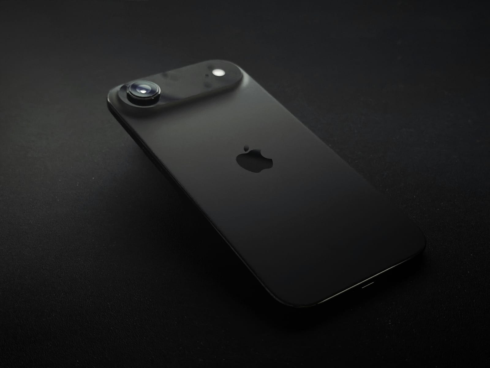 Schwarzes iPhone mit Apple-Logo auf dunklem Hintergrund