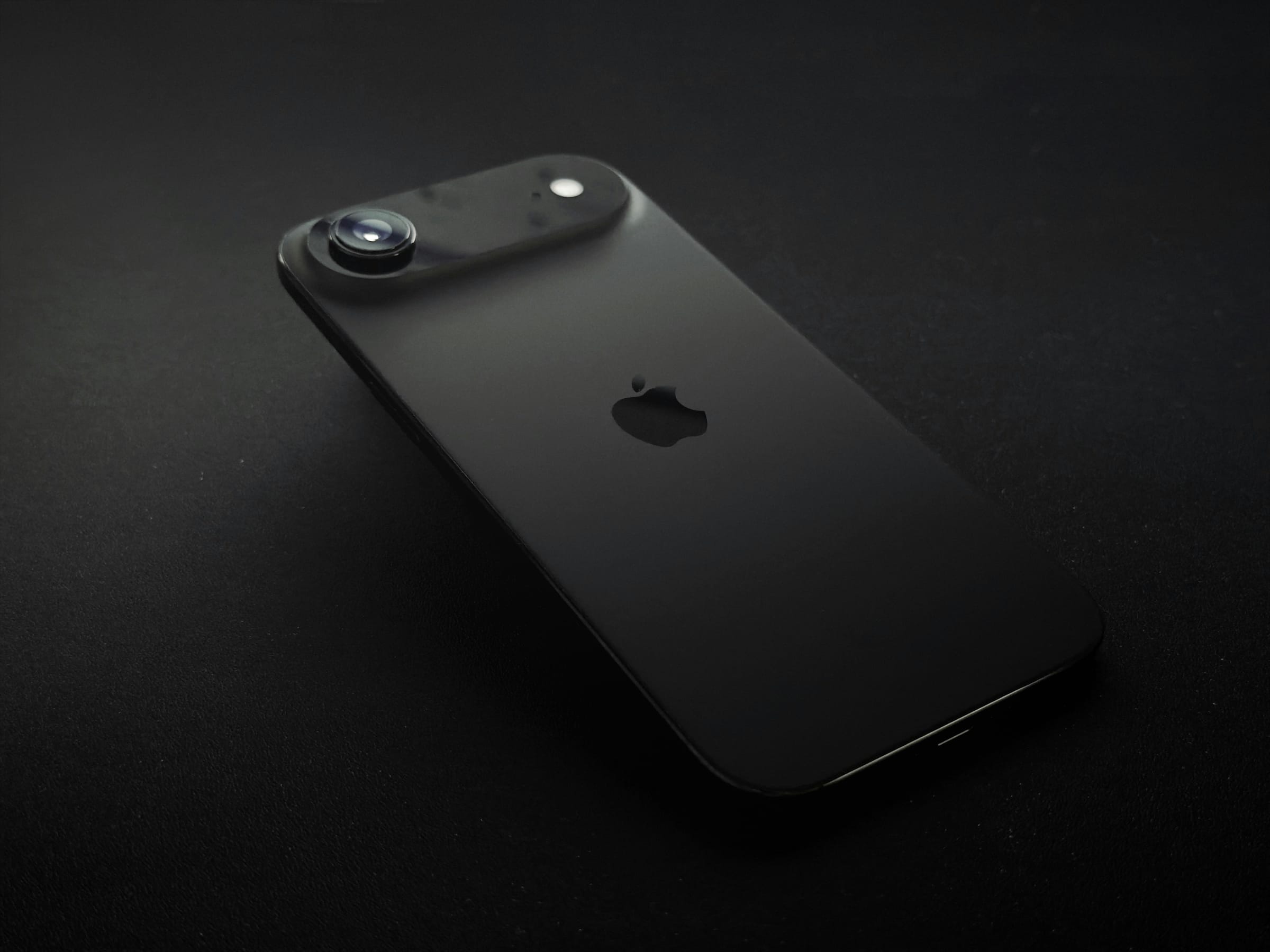 Schwarzes iPhone mit Apple-Logo auf dunklem Hintergrund
